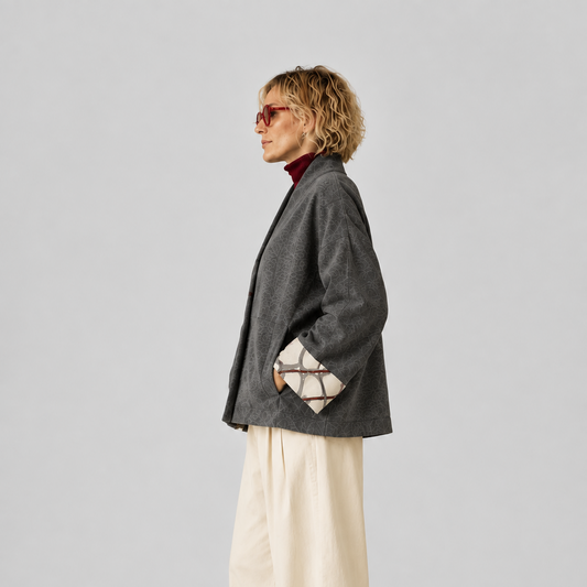 Veste Nuno Milano Aki en laine mérinos feutrée grise, vue de côté, avec poignets retroussés contrastés à imprimé abstrait crème et bordeaux et silhouette courte décontractée