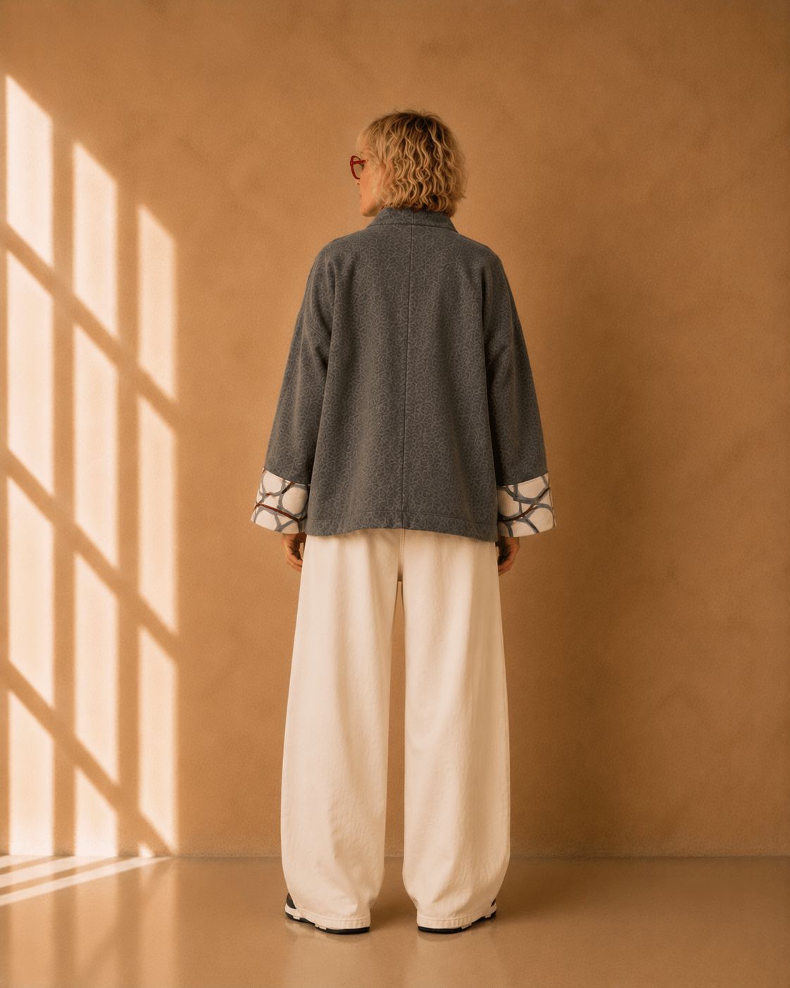 Nuno Milano Aki grey felted Merino wool jacket, back view, cropped length with centre back seam detail and contrasting cream and burgundy abstract-print cuffs