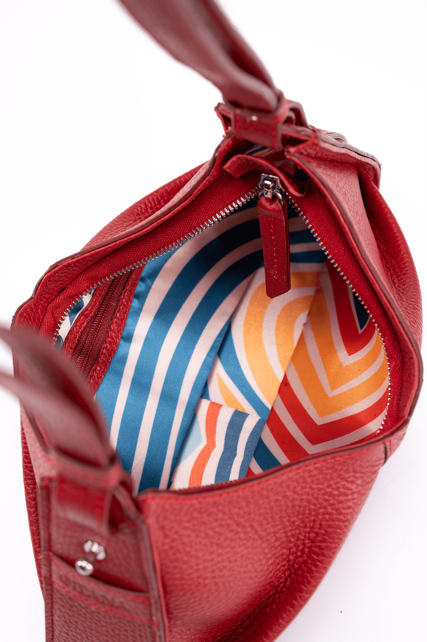 The inside of a luxury red leather shoulder bag. The photo focuses on the colourful inside lining.