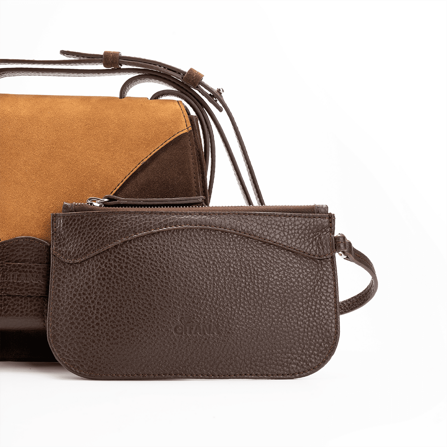 A front view of a luxury crossbody bag in chocolate and caramel suede and matching pouch on attaching strap.