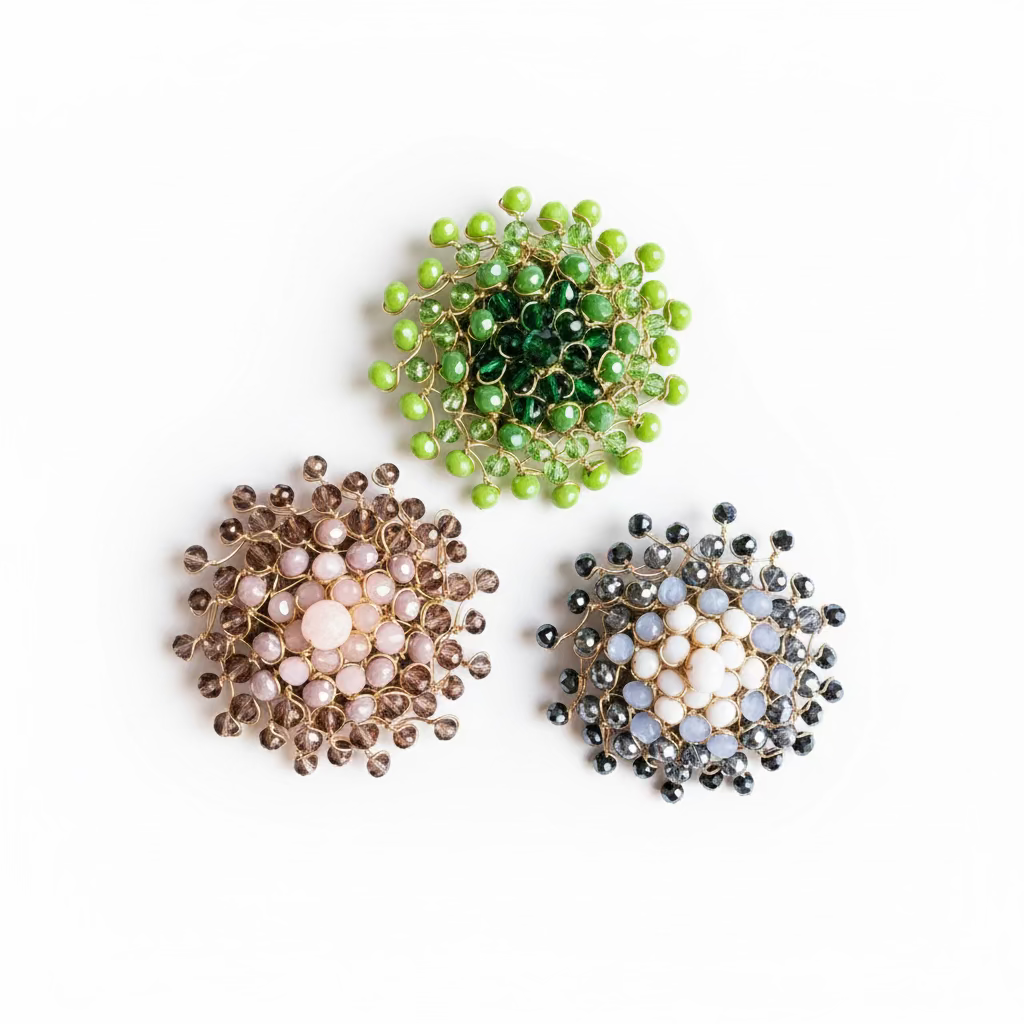 Three handmade gold wire floral brooches with faceted beads, arranged on a textured hot pink background. One brooch features light pink beads, one features dark green beads, and the third features light blue and white beads.