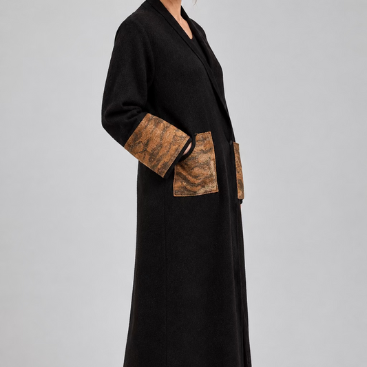 Vue de côté d'une femme portant un long manteau peignoir kimono marron foncé en laine mérinos, avec grandes poches plaquées et poignets marron texturés en feutre Nuno.