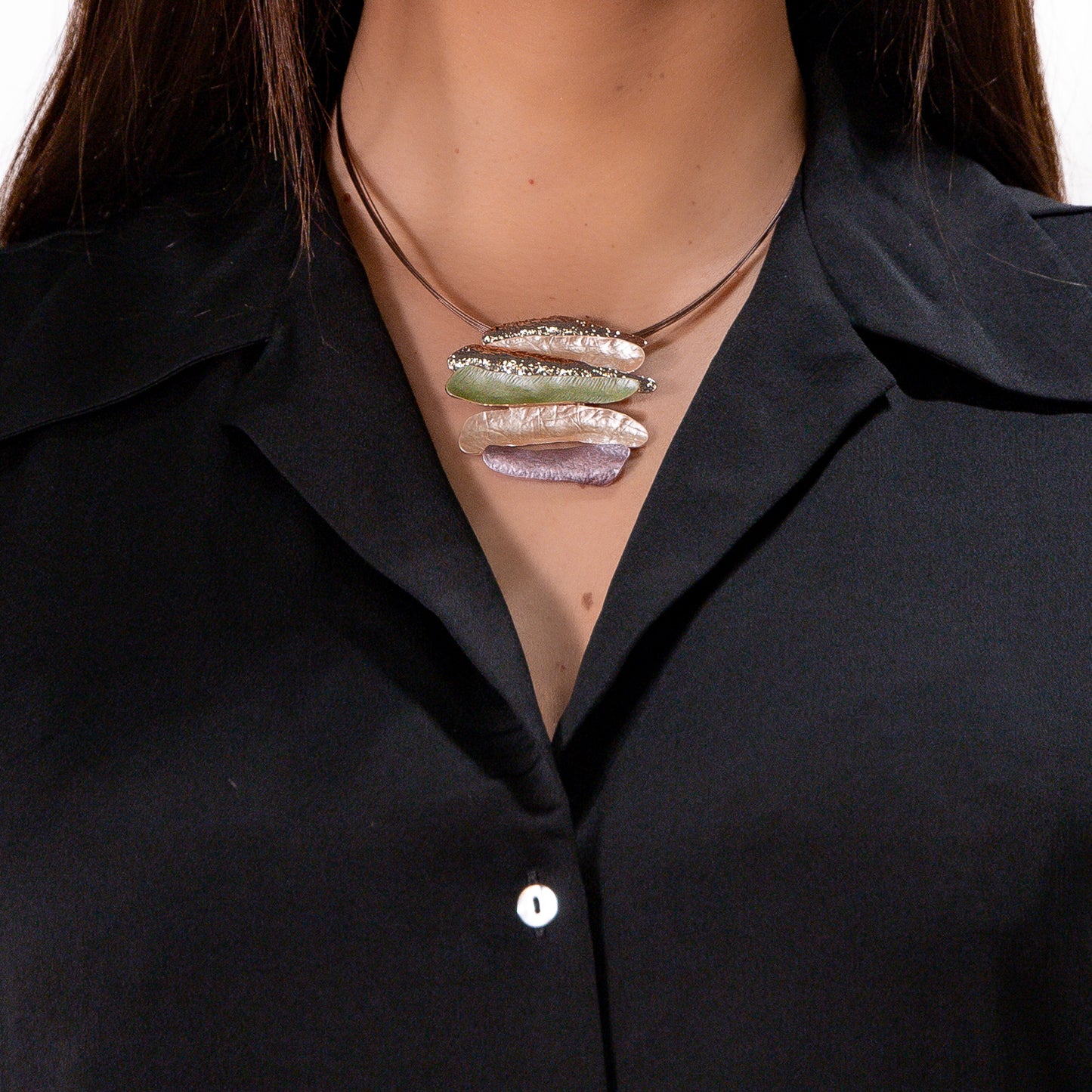Necklace with a multicolored pendant on a person wearing a black shirt.