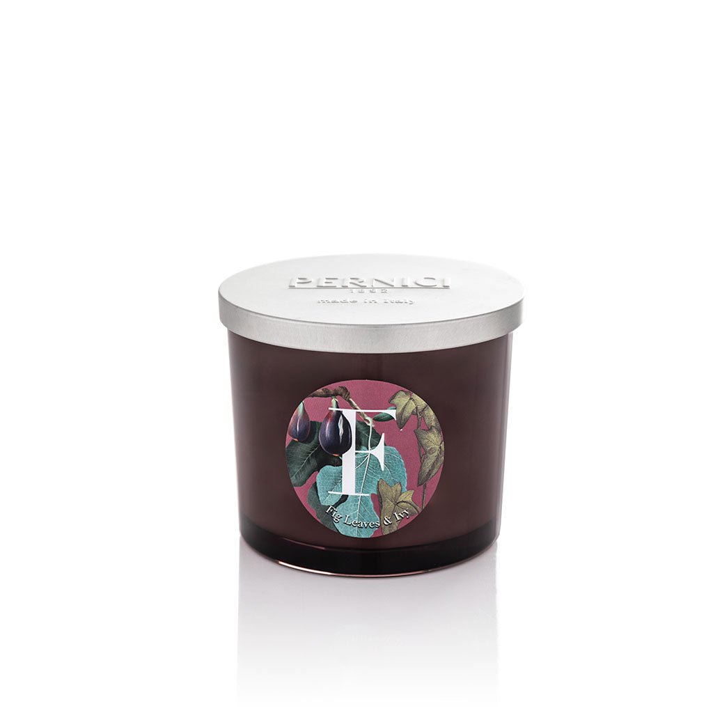 Cereria Pernici Elementi Fig Leaves & Ivy 200g scented candle in a dark amber glass jar with silver Pernici lid and circular botanical fig and ivy label on a pink background, product shot on white background