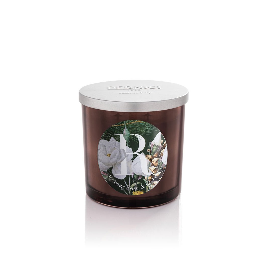 Cereria Pernici Elementi Iceberg Rose & Cedar 200g scented candle in a dark amber glass jar with silver Pernici lid and circular label featuring white iceberg rose, pine needles and cedar cones on a dark green background, product shot on white background