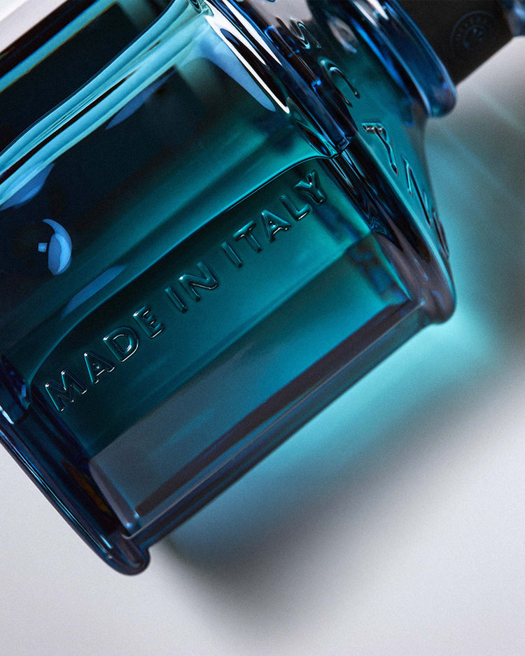 Close-up of a teal glass diffuser bottle embossed with "Made in Italy" by Erbario Toscano