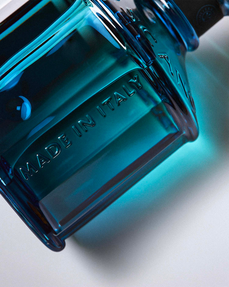 Close-up of a teal glass diffuser bottle embossed with "Made in Italy" by Erbario Toscano