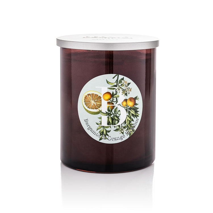 Bergamot & Orange Blossom scented candle in a dark amber glass jar with silver lid, featuring a botanical illustrated label with citrus fruits and orange blossom, product shot on white background