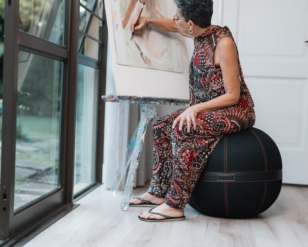 Woman using a Balanball as a footrest while reading on a sofa in a living roo
