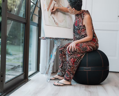 Woman using a Balanball as a footrest while reading on a sofa in a living roo