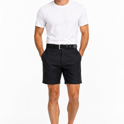 A man wearing black linen shorts, a black woven belt with a satin silver buckle and a white t-shirt on a white background.