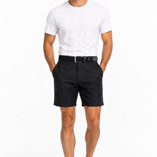 Un homme en short de lin noir, ceinture tressée noire à boucle argent satiné et t-shirt blanc, sur fond blanc.