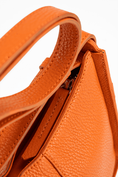 Close-up of an orange Italian Pebble Leather handbag with a textured handle.
