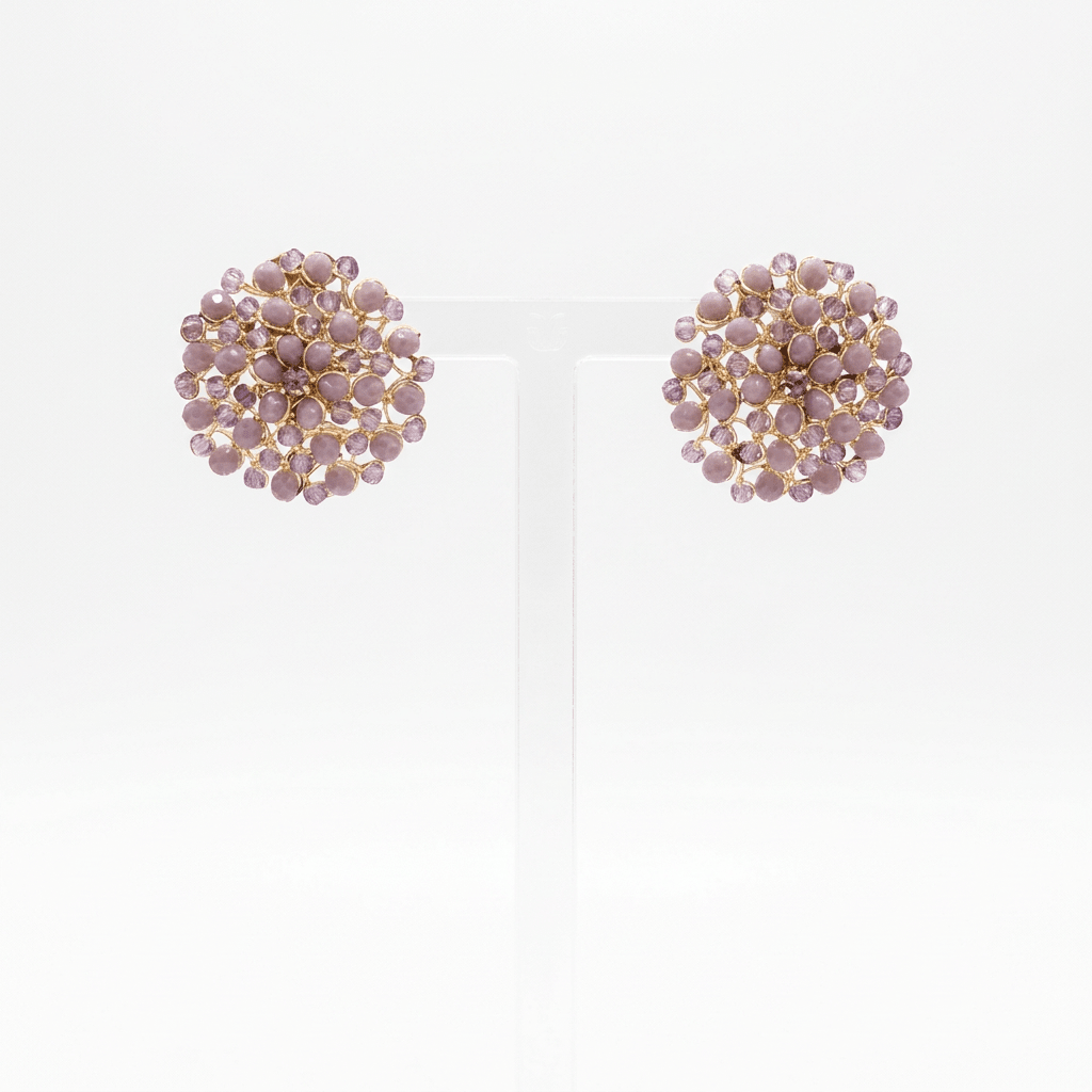 A lavender faceted button mandala earring on a perspex stand against a white background. 