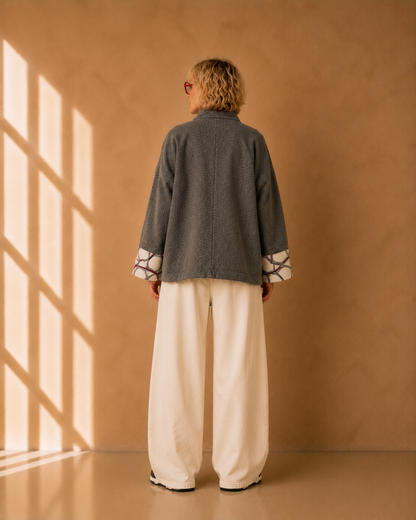Nuno Milano Aki grey felted Merino wool jacket, back view, cropped length with centre back seam detail and contrasting cream and burgundy abstract-print cuffs