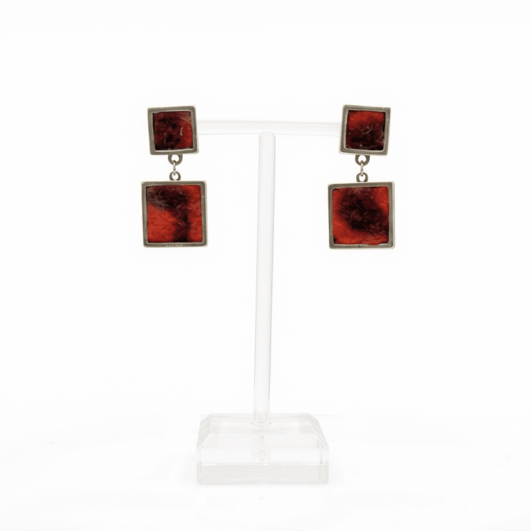 A pair of square drop earrings displayed on a clear acrylic T-stand against a white background. Each earring features a top silver-tone square with a black and red marbled pattern, connected by a small silver chain to a larger bottom square of the same design.