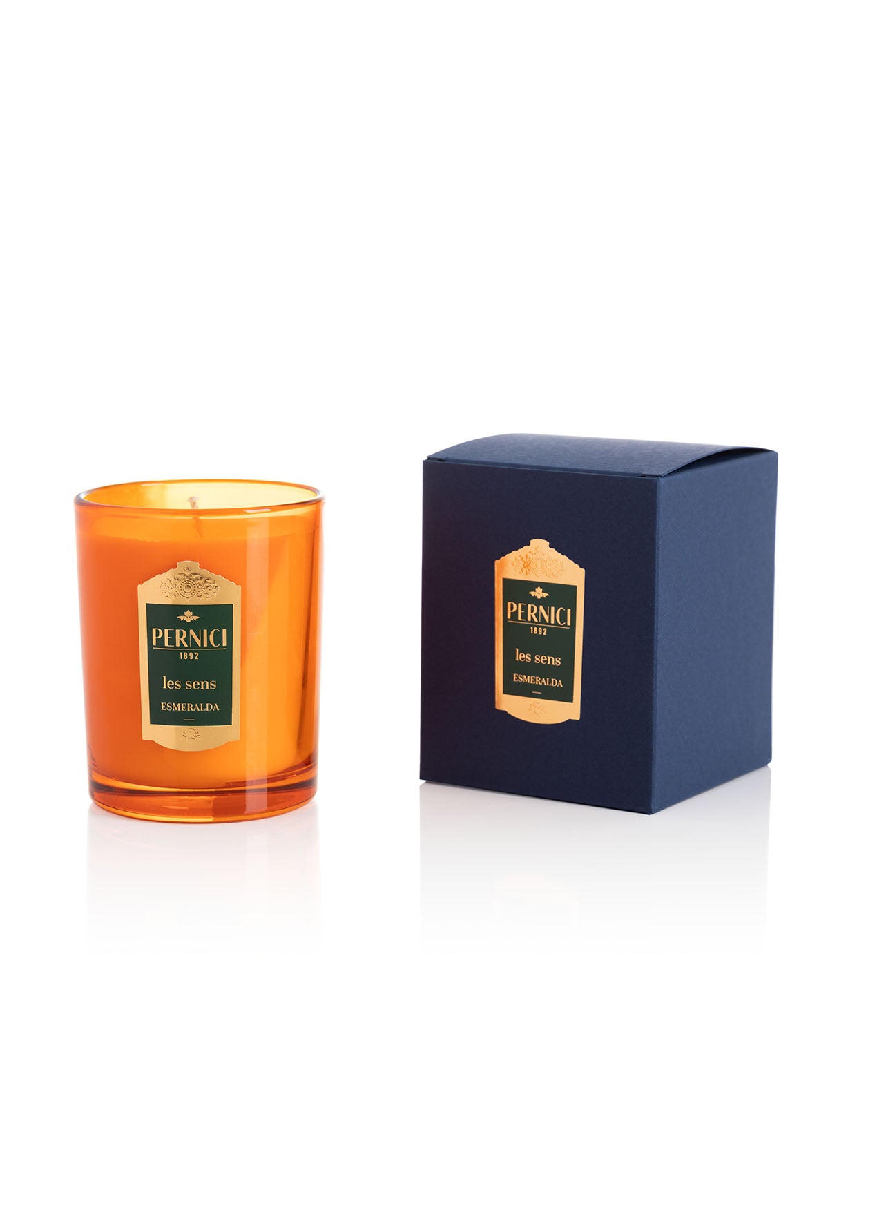 Cereria Pernici Les Sens Esmeralda 70g scented candle in a deep amber glass tumbler with gold Pernici 1892 label, shown alongside its navy blue gift box with gold foil label, product shot on white background
