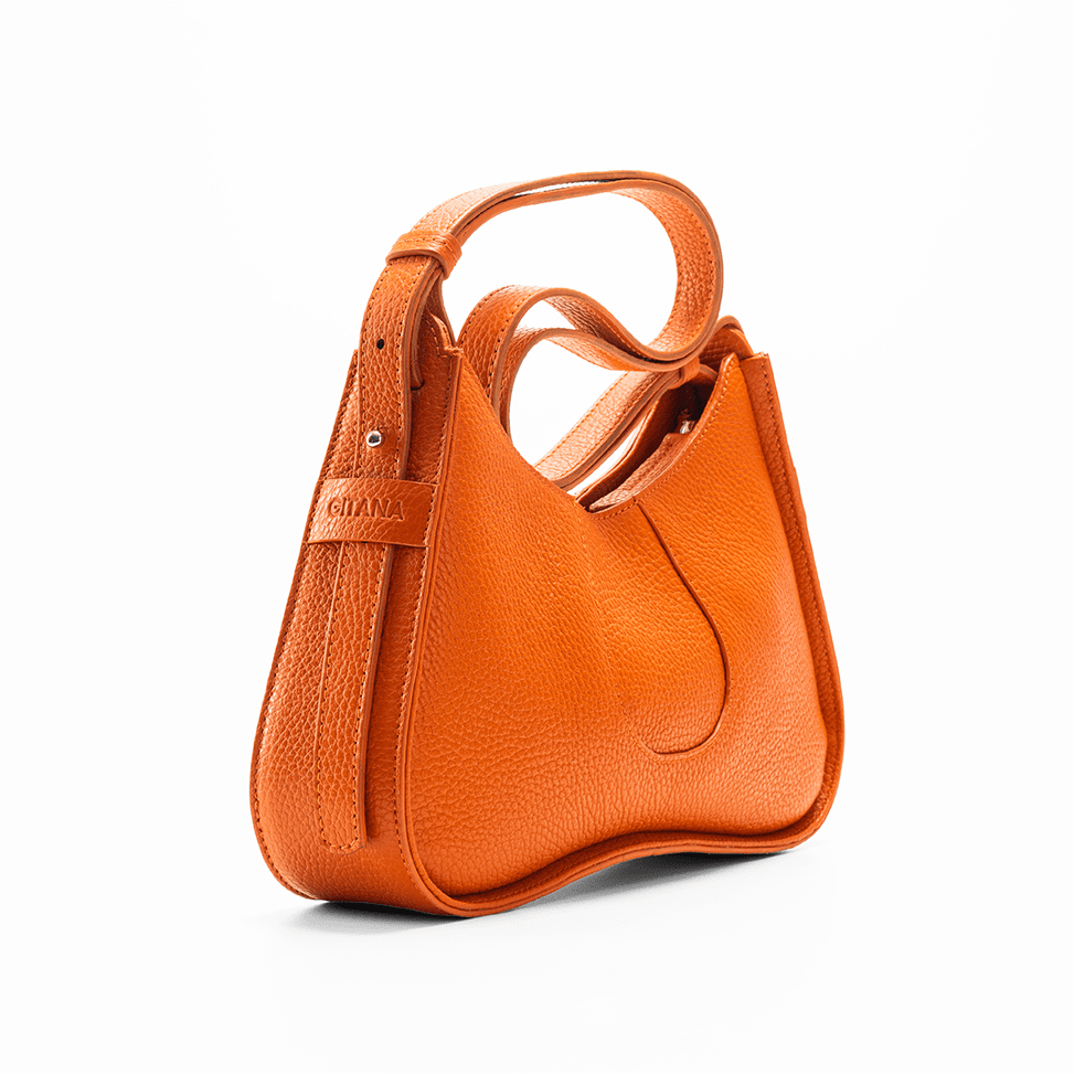 The Side View of an Orange Shoulder Bag in Italian Pebble Leather which Focuses on the Adjustable Shoulder Strap and the "Gitana" Band Name.