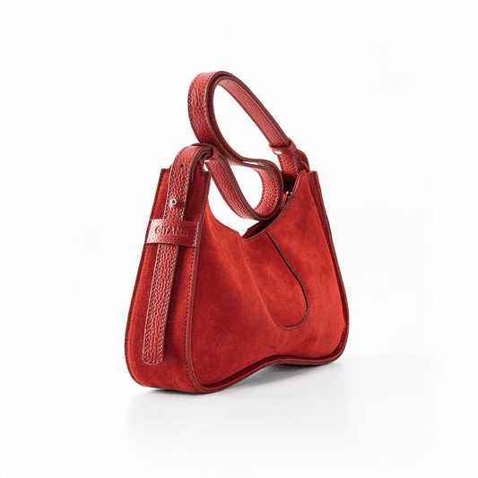 The Side View of Aria Shoulder Bag in Red Italian Suede Leather with Red Pebble Leather Trim.  Focus is on the Adjustable Shoulder Strap and the "Gitana" Brand