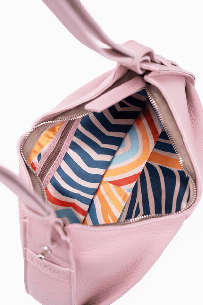The inside of a luxury petal pink leather shoulder bag.  The photo focuses on the colourful inside lining.