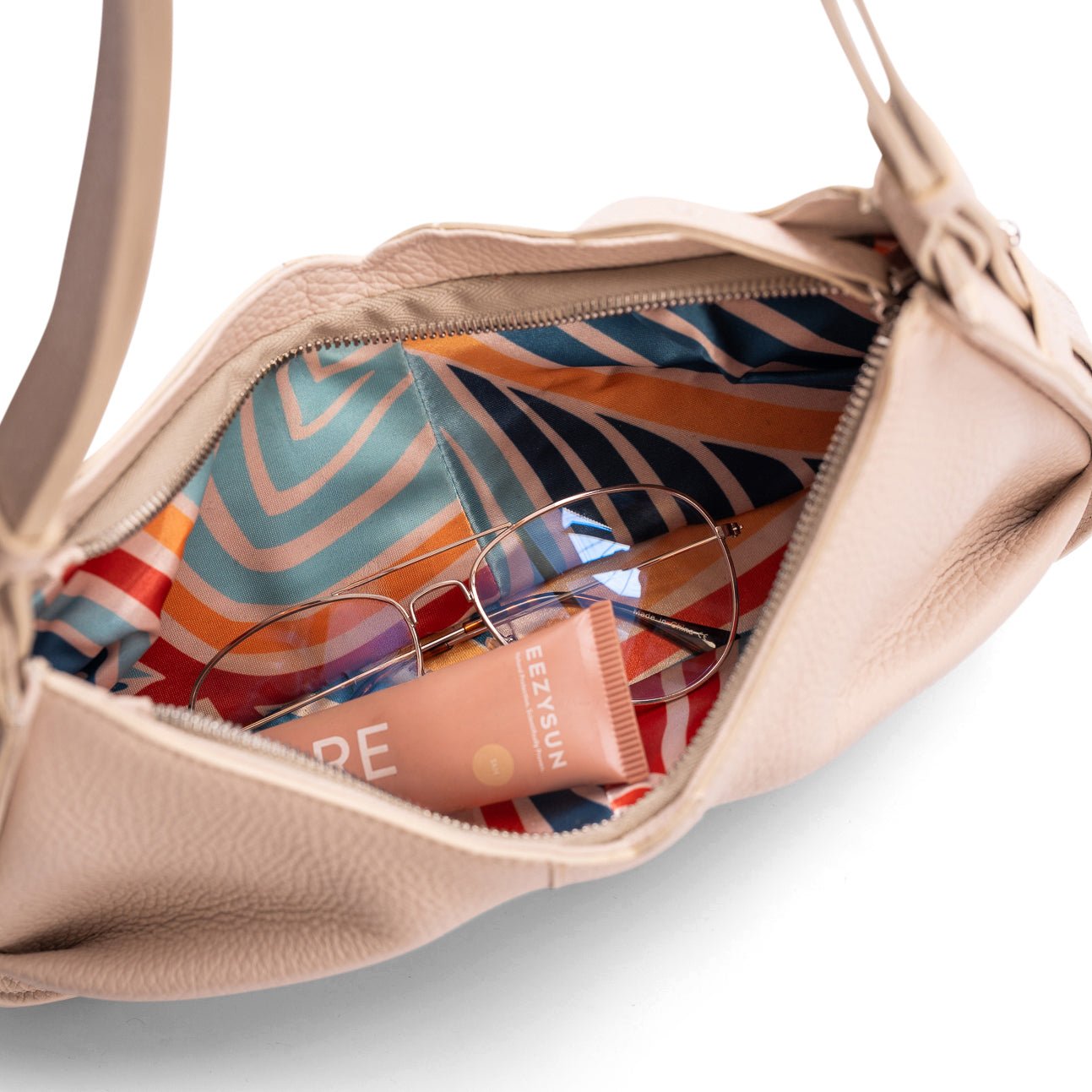 The inside of a luxury beige leather shoulder bag.  The photo focuses on the colourful inside lining.