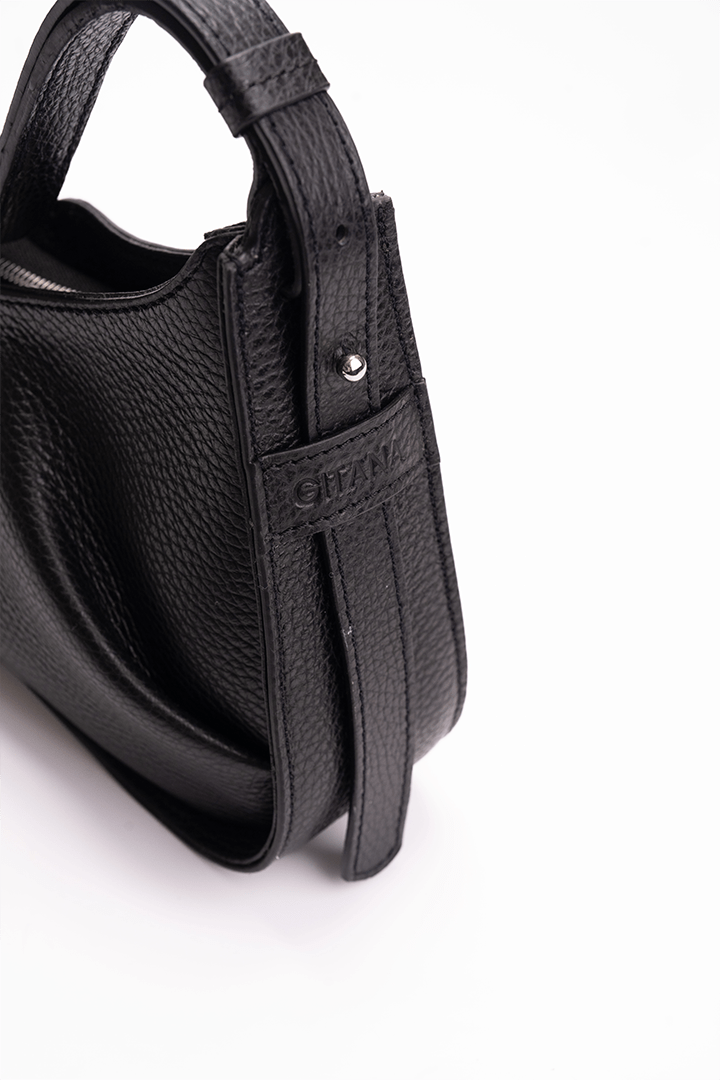 Close-up of the gusset of a luxury black leather shoulder bag with the Gitana branding 