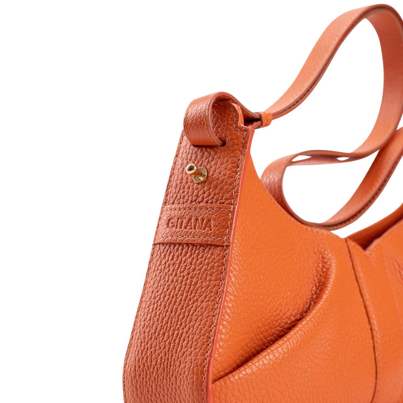 Close-up of the gusset of a luxury orange leather shoulder bag with the Gitana branding and a swirl shoulder strap.