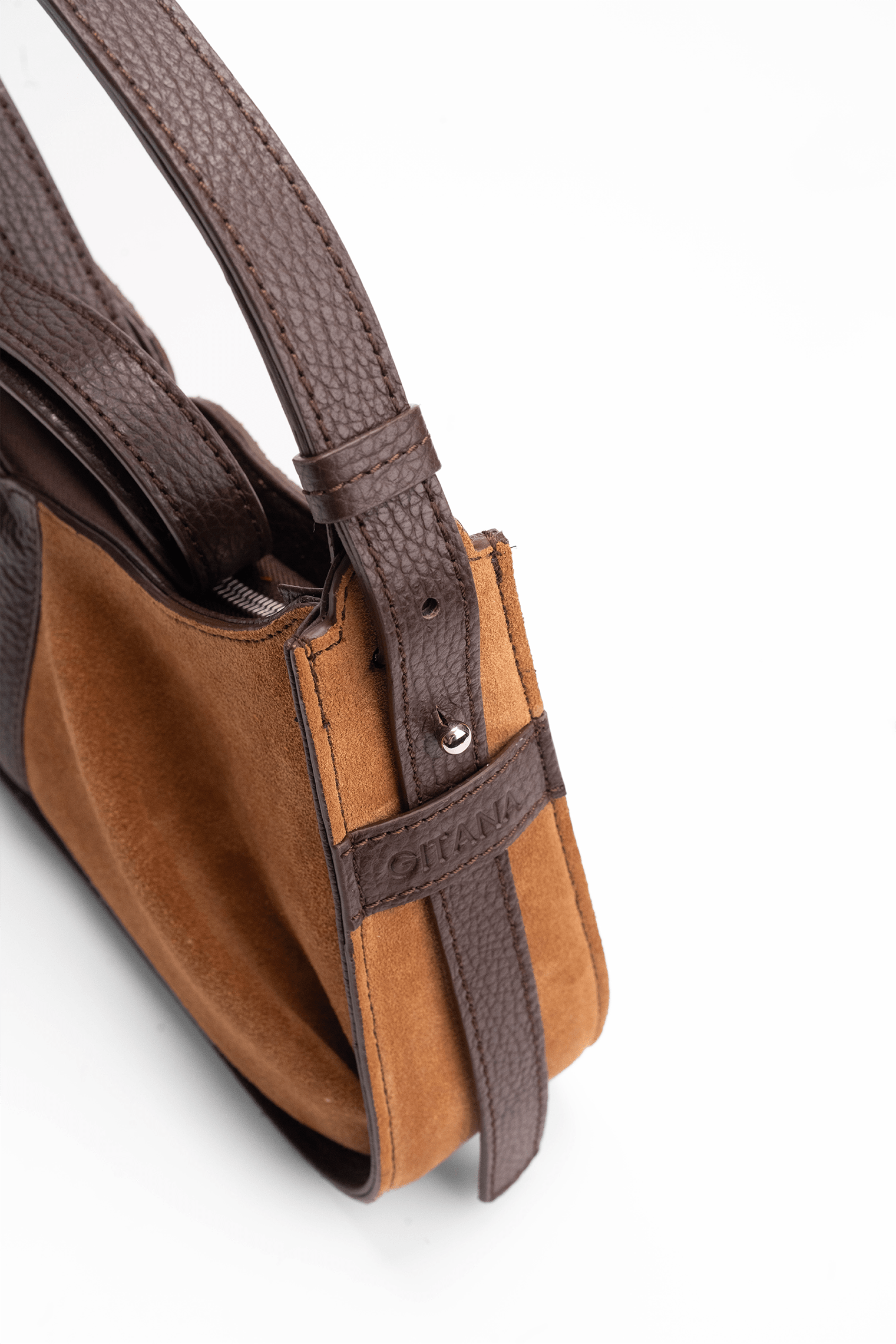 Close-up of the gusset of a luxury caramel and brown suede shoulder bag with the Gitana branding and a swirl shoulder strap.