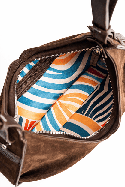 The inside of a luxury brown suede shoulder bag.  The photo focuses on the colourful inside lining.