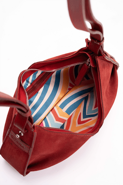 The inside of a luxury red suede shoulder bag.  The photo focuses on the colourful inside lining.