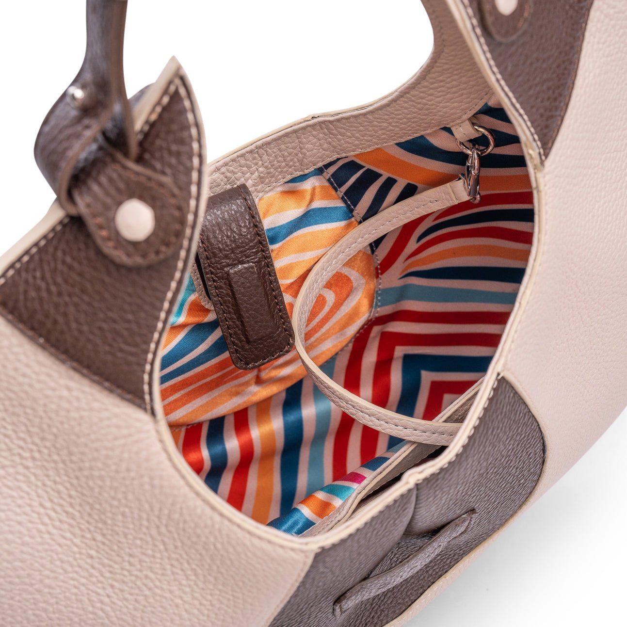 A close-up view of the inner colourful lining of a luxury cream and brown elliptical leather tote bag showcased  on a white background.  