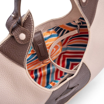 A close-up view of the inner colourful lining of a luxury cream and brown elliptical leather tote bag showcased  on a white background.  