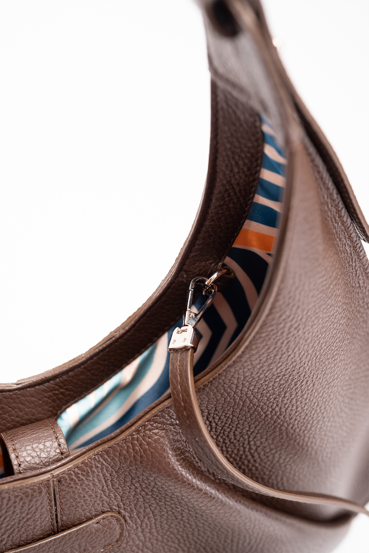 A close-up view of a brown Italian pebble caf leather tote bag with a striped lining on a white background