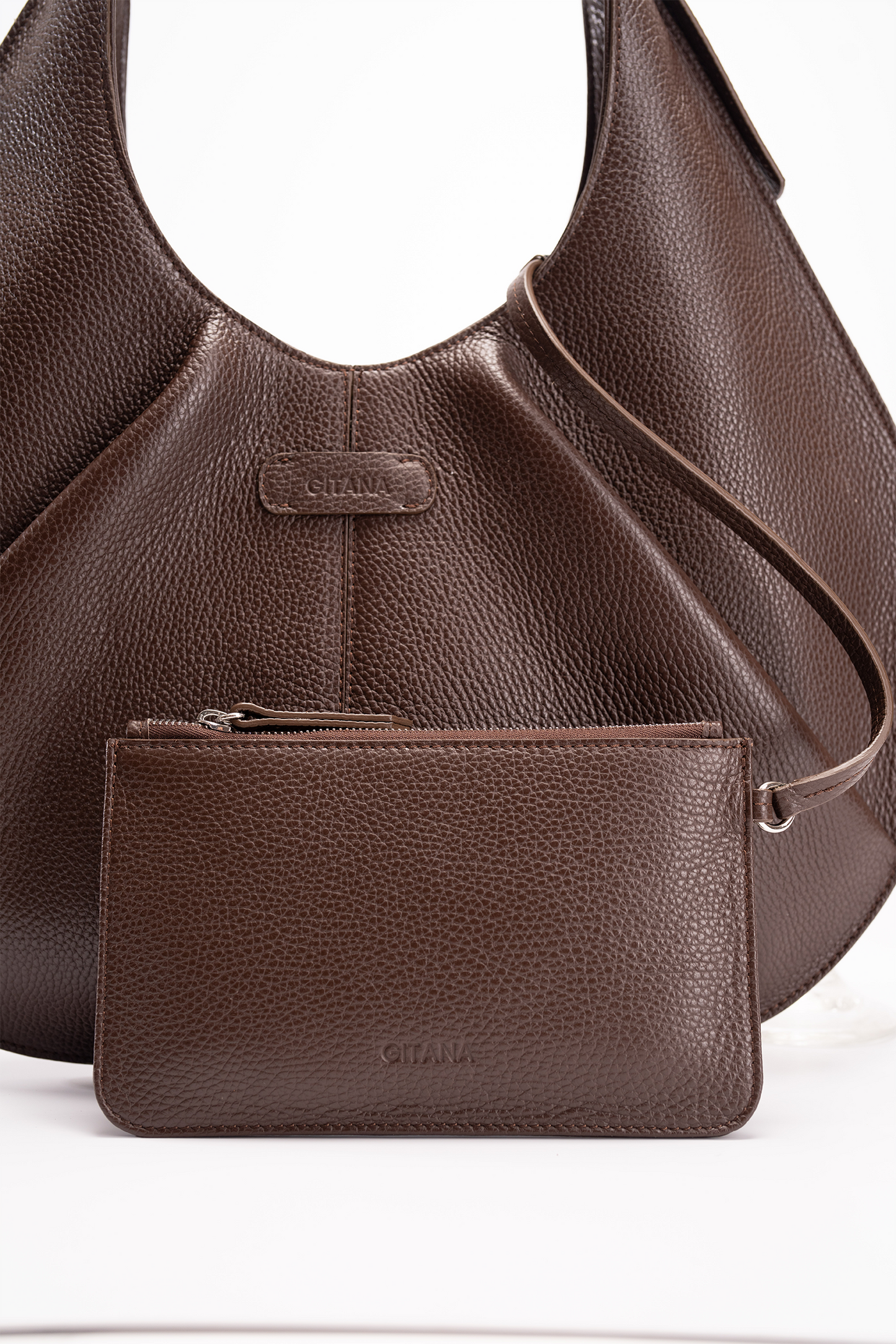 A brown Italian pebble calf leather handbag and matching pouch on a white background.