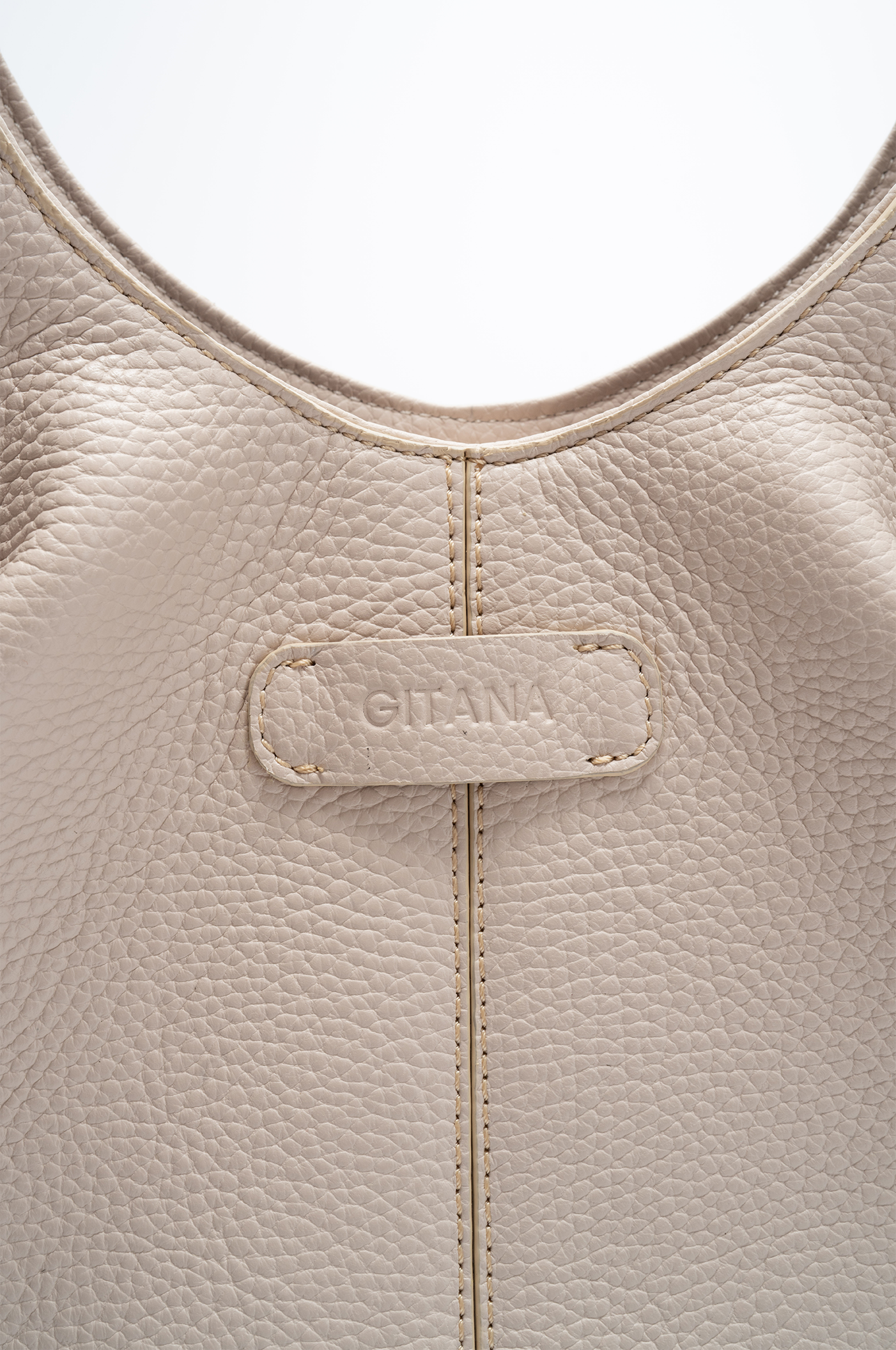 Close-up of a beige Italian pebble calf leather tote handbag with 'Gitana' branding.