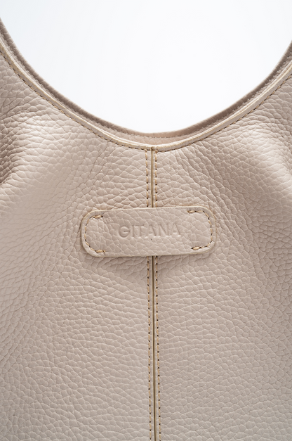 Close-up of a beige Italian pebble calf leather tote handbag with 'Gitana' branding.