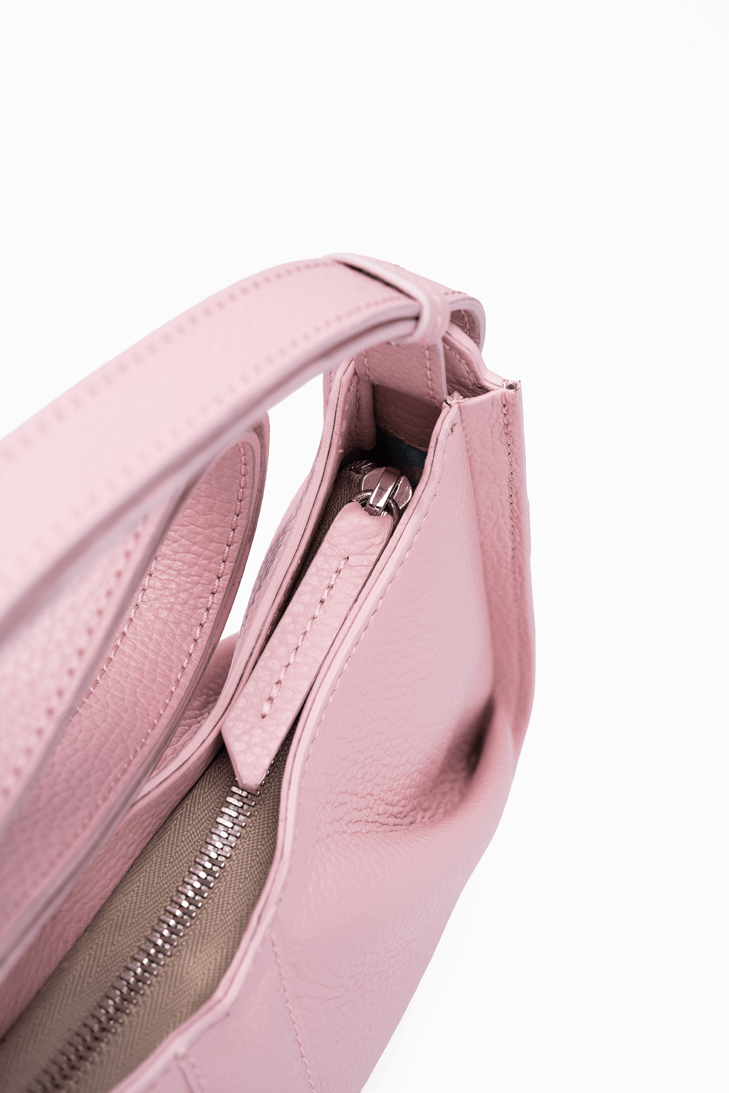 Close-up of a petal pink shoulder handbag with a zipper on a white background.