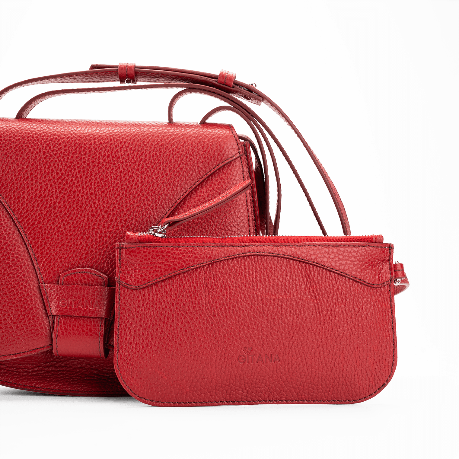 Close-up of a red Italian pebble calf leather designer pouch attached to a luxury handbag by a strap, showcasing the visible brand name  