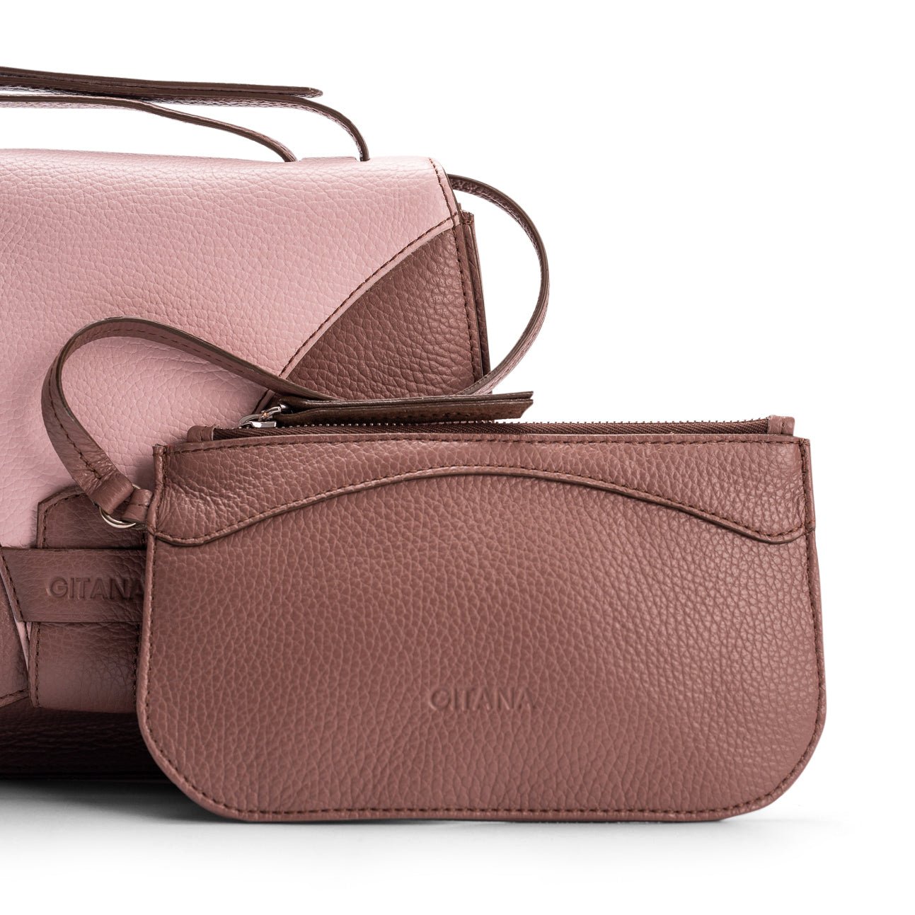 Close-up of a light brown leather designer pouch attached to a luxury handbag by a strap, showcasing the visible brand name 