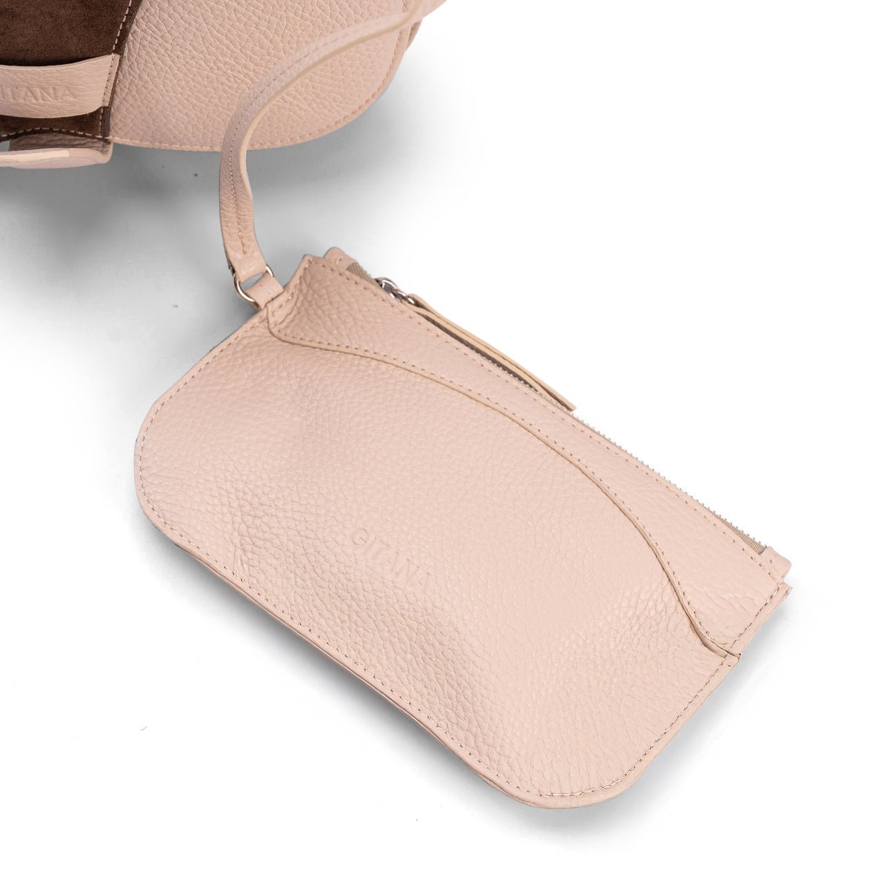 Close-up of a beige leather designer pouch attached to a luxury handbag by a strap, showcasing the visible brand name, on a white background.