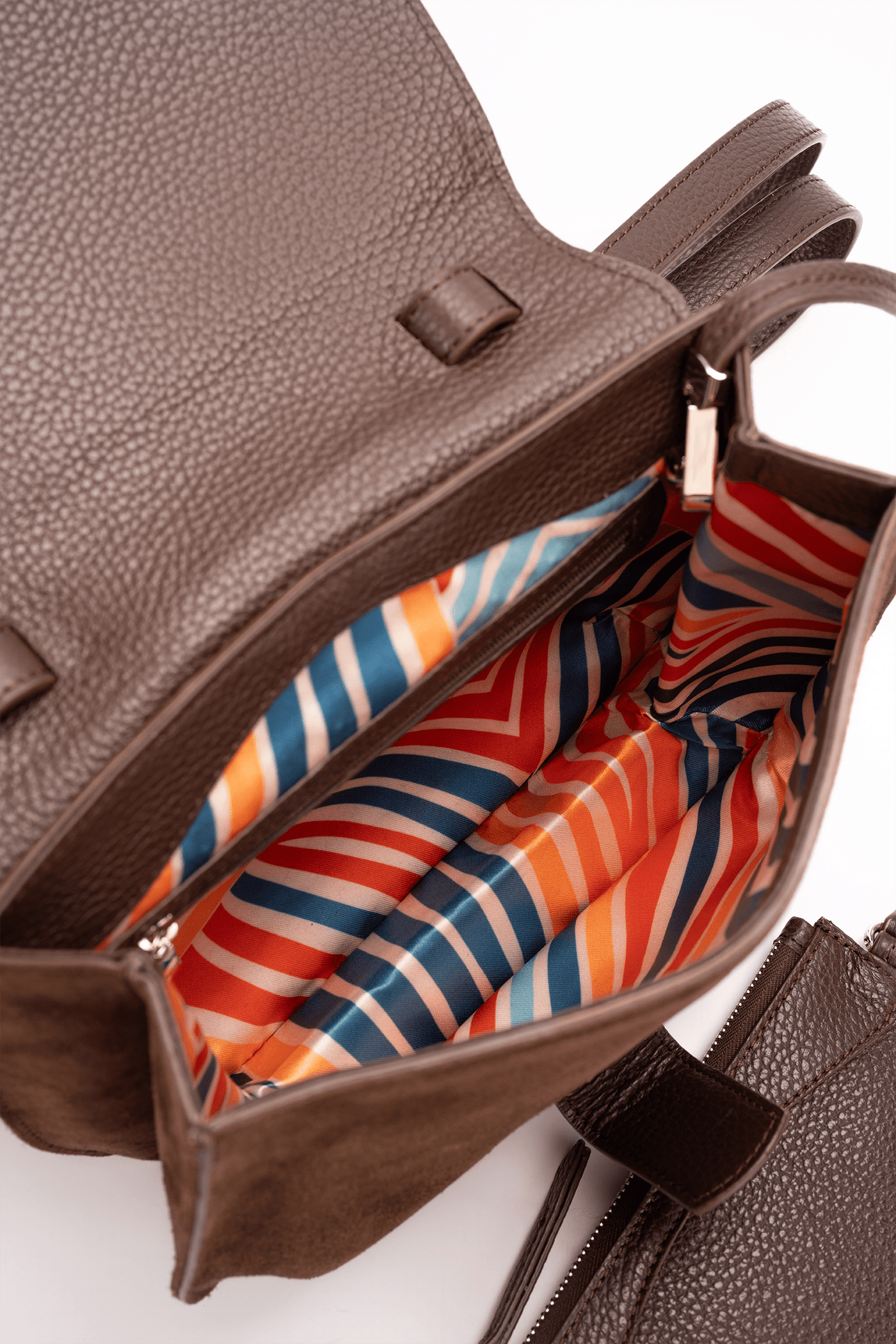 Internal view of a medium-sized chocolate and caramel luxury women’s handbag showing its colourful patterned lining.