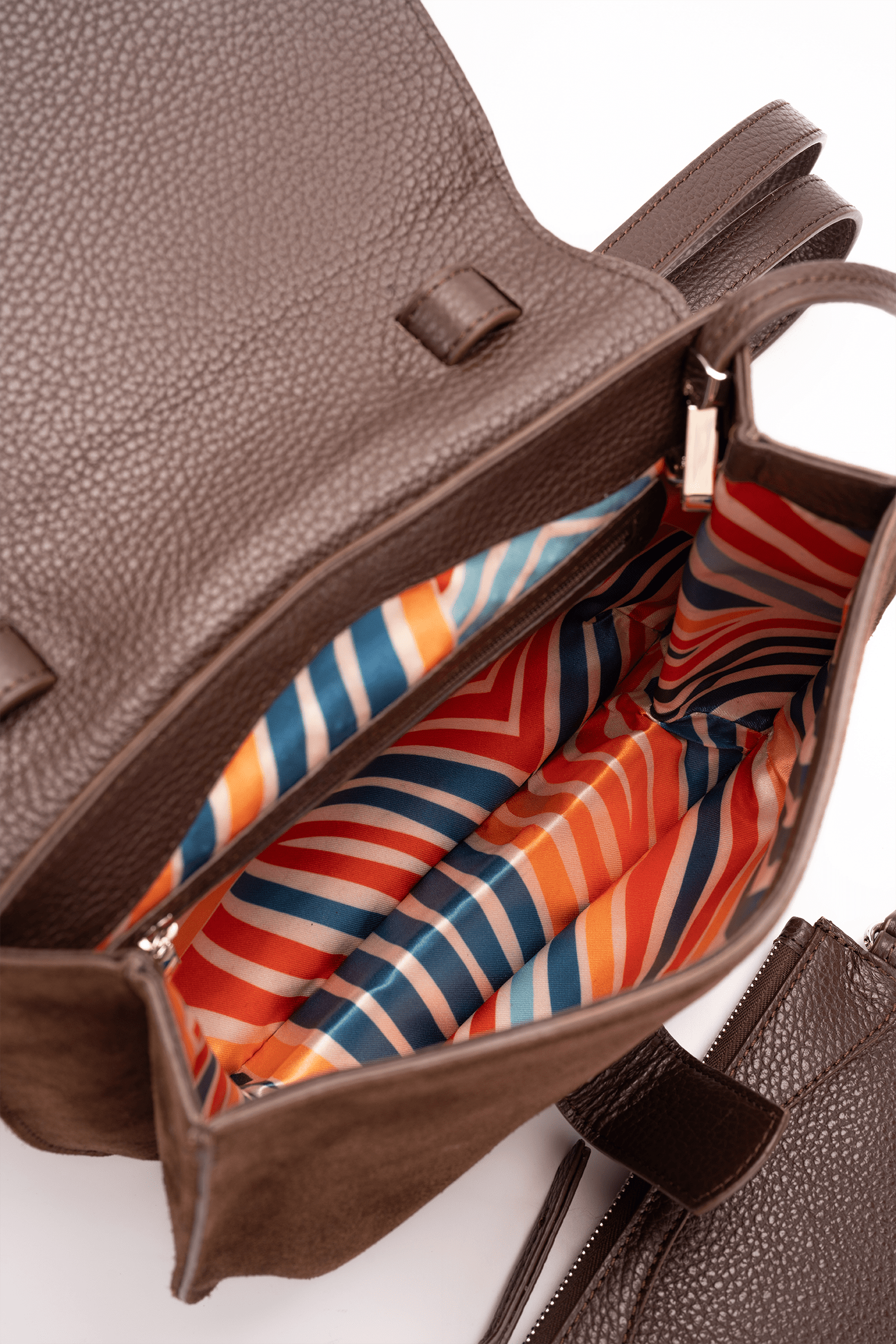 Internal view of a medium-sized chocolate and caramel luxury women’s handbag showing its colourful patterned lining.