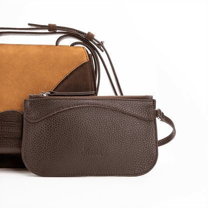 A front view of a luxury crossbody bag in chocolate and caramel suede and matching pouch on attaching strap.