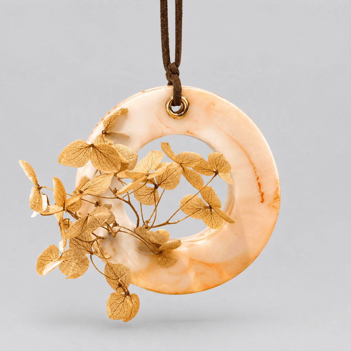A Golden Peach  scented cupboard wax tablet with a leather string on a white background