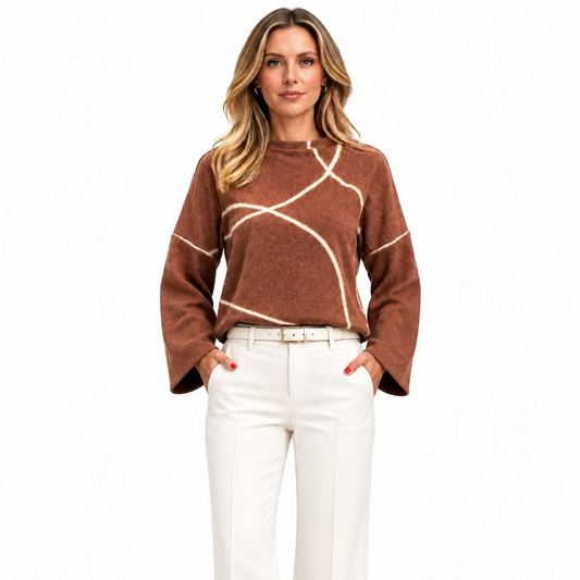 A woman wearing a cropped, long-sleeve knit top in a warm brownish-rose color with abstract white line patterns, paired with cream tailored bants pants.