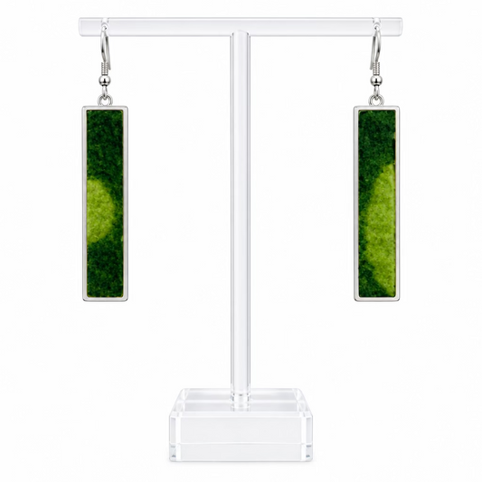 A pair of slim long rectangular pendant earrings on a perspex stand against a white background.  The earrings have a lime and dark green wool centre.