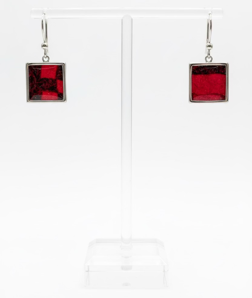 A pair of square drop earrings with deep red center panels in Nuno Felt and silver borders, displayed on a clear acrylic stand against a white background.