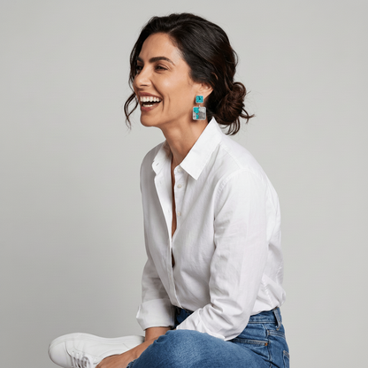 Model wearing Costa double pendant earrings in turquoise and grey marbled Nuno Felt, styled with a white linen shirt and jeans
