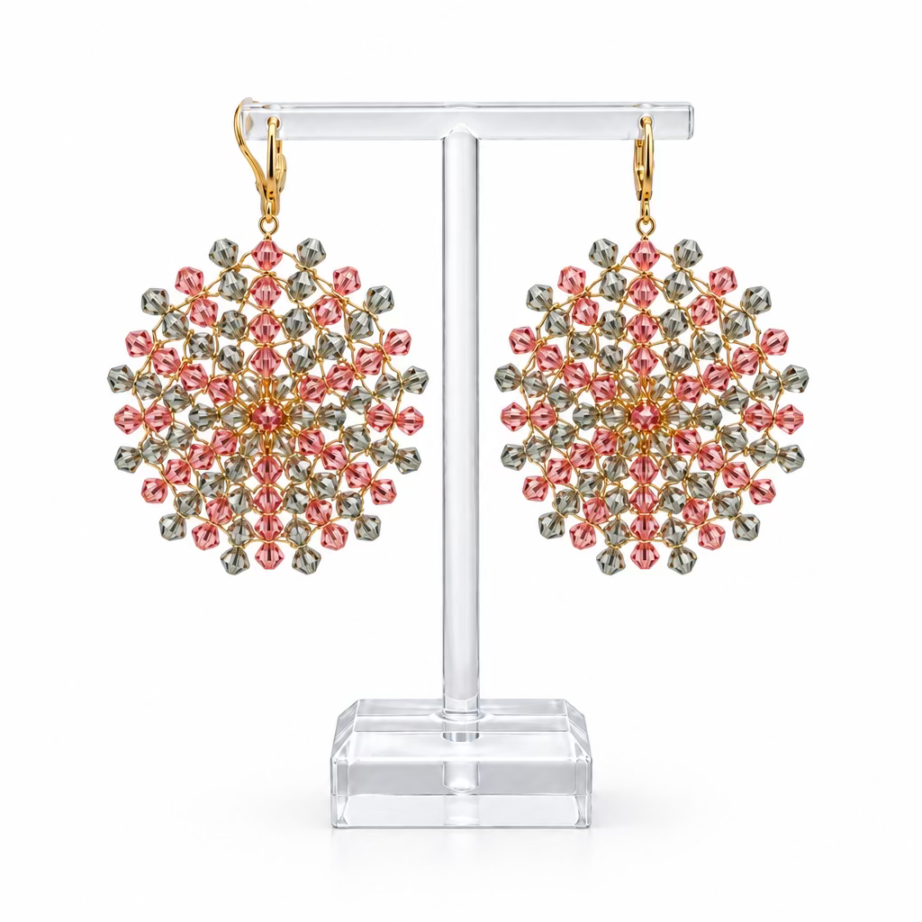 Une paire de boucles d'oreilles Mandala en cristaux Swarovski rose et gris-vert enfilés sur fil plaqué or, sur fond blanc.