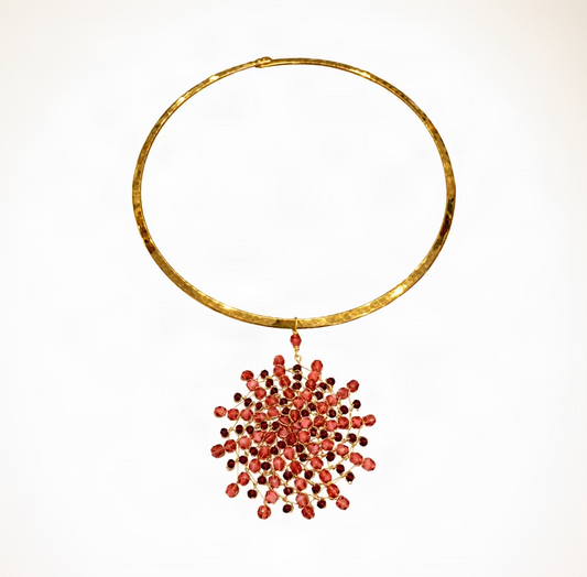 A gold-toned circular collar necklace with a dangling cluster of red faceted beads, displayed on a white background.